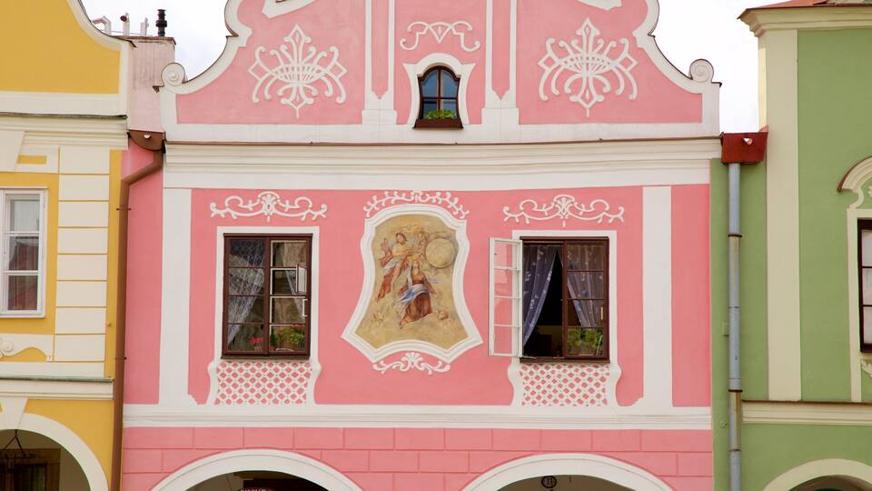 A pink building with ornate white decorations and a religious mural.