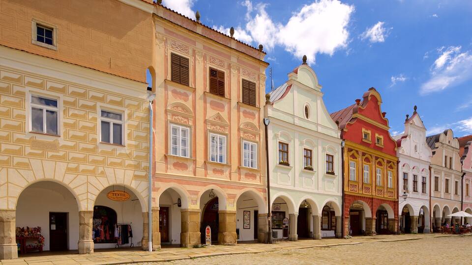 A historic European street with colorful buildings, arches, and cobblestone pavement.