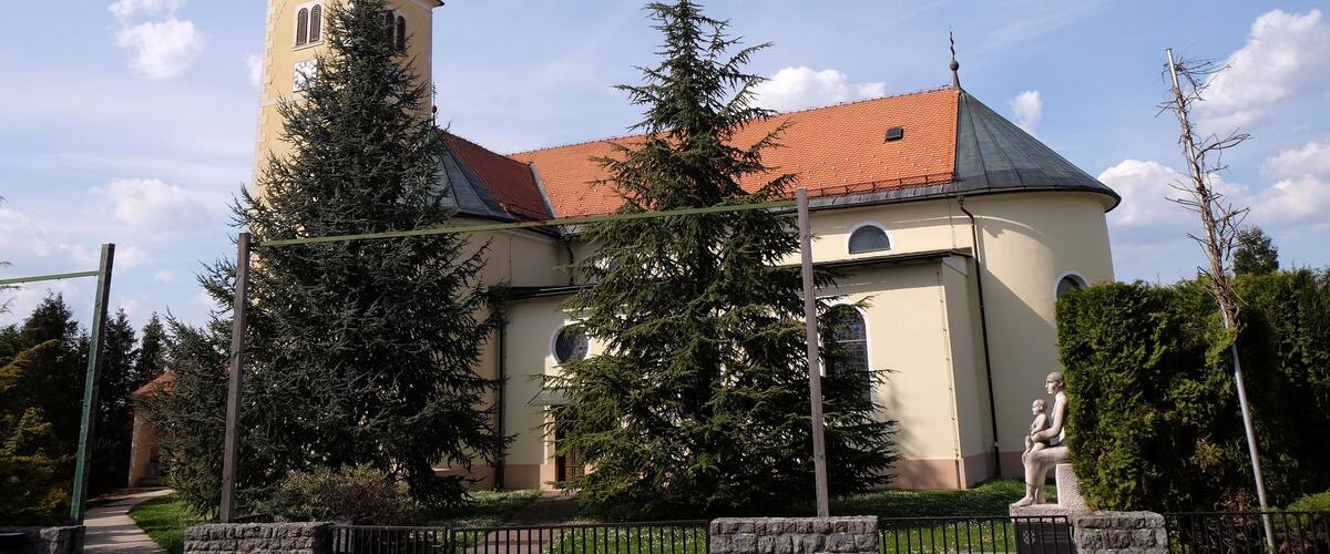A church with a tall bell tower and a red-tiled roof.