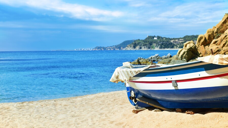 an old fishing boat stranded in the quiet beach Platja de Sa Caleta in Lloret de Mar, in the Costa Brava, Spain; Shutterstock ID 683902255; purchase_order: Comps; job: ; client: ; other: