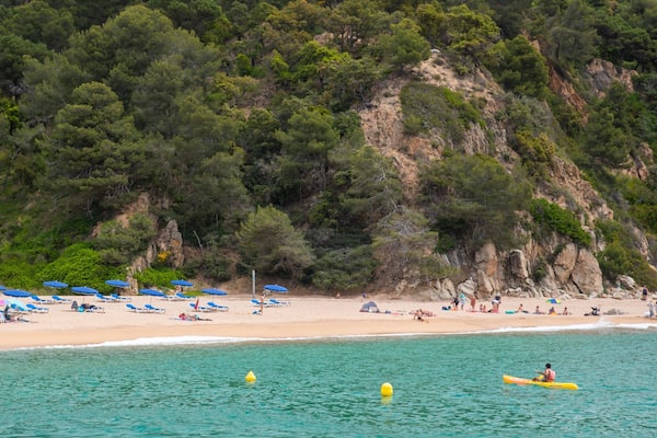 Cala Canyelles Beach featuring rocky coastline, a sandy beach and general coastal views