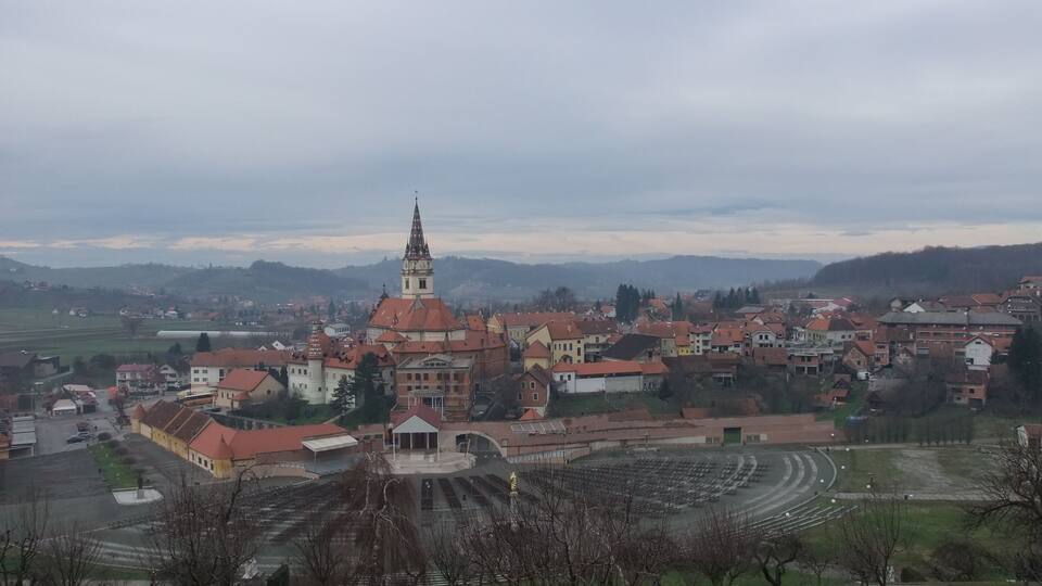 A town with a prominent church tower, a large open plaza, and surrounding residential buildings.