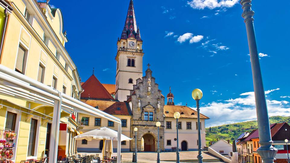 A town square with a church, outdoor cafe, and cobblestone streets.