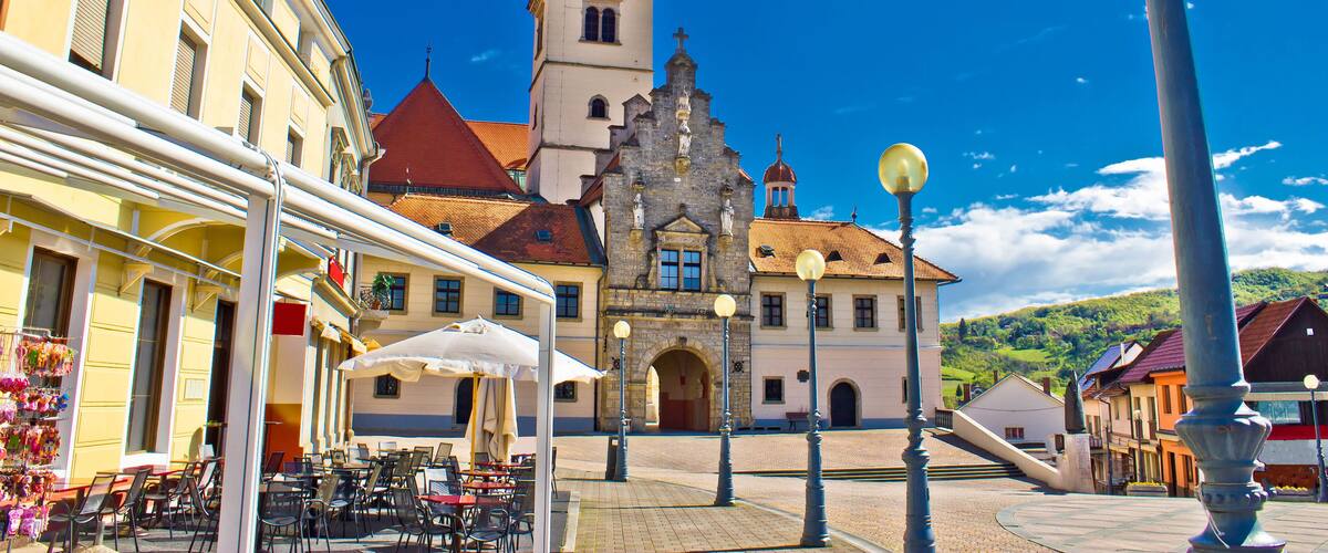 A town square with a church, outdoor cafe, and cobblestone streets.