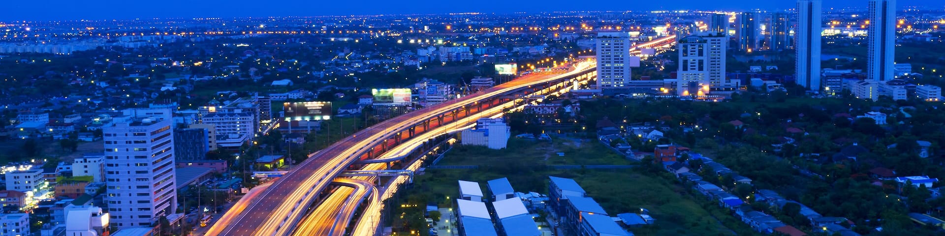 A cityscape at dusk with a prominent highway and surrounding buildings.