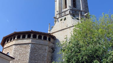 Een historische toren met een klok, omringd door stenen muren en een boom.