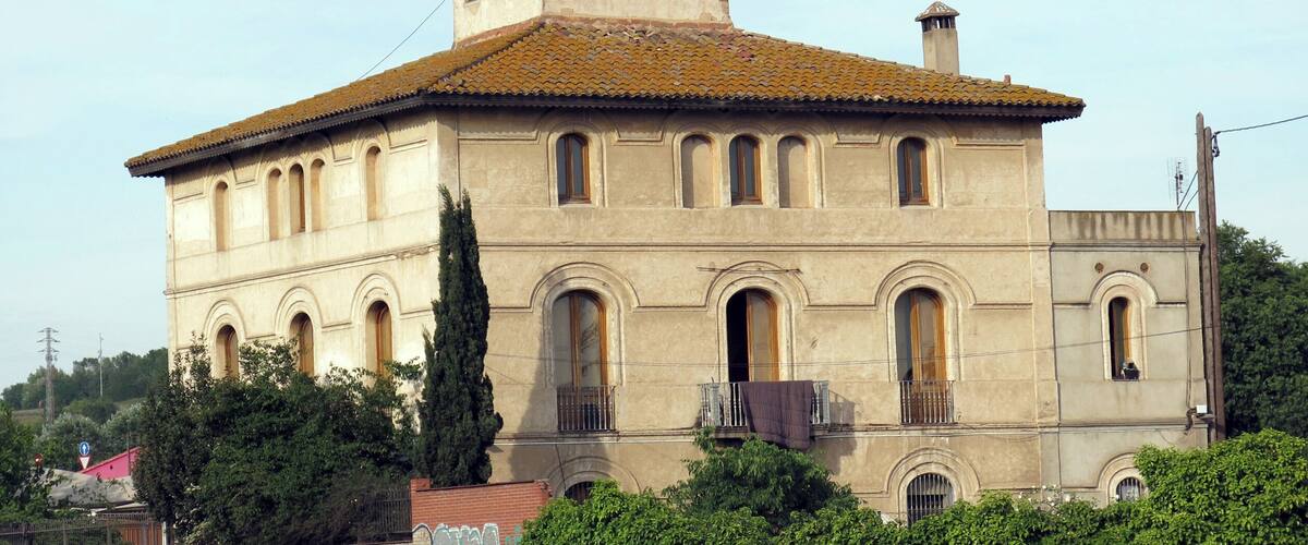 A historic building with a tiled roof, arched windows, and a bell tower.