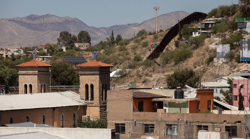 Afternoon sun shines on the historic downtown church in central Heroica Nogales, Sonora, Mexico, with the USA border wall in the distance.