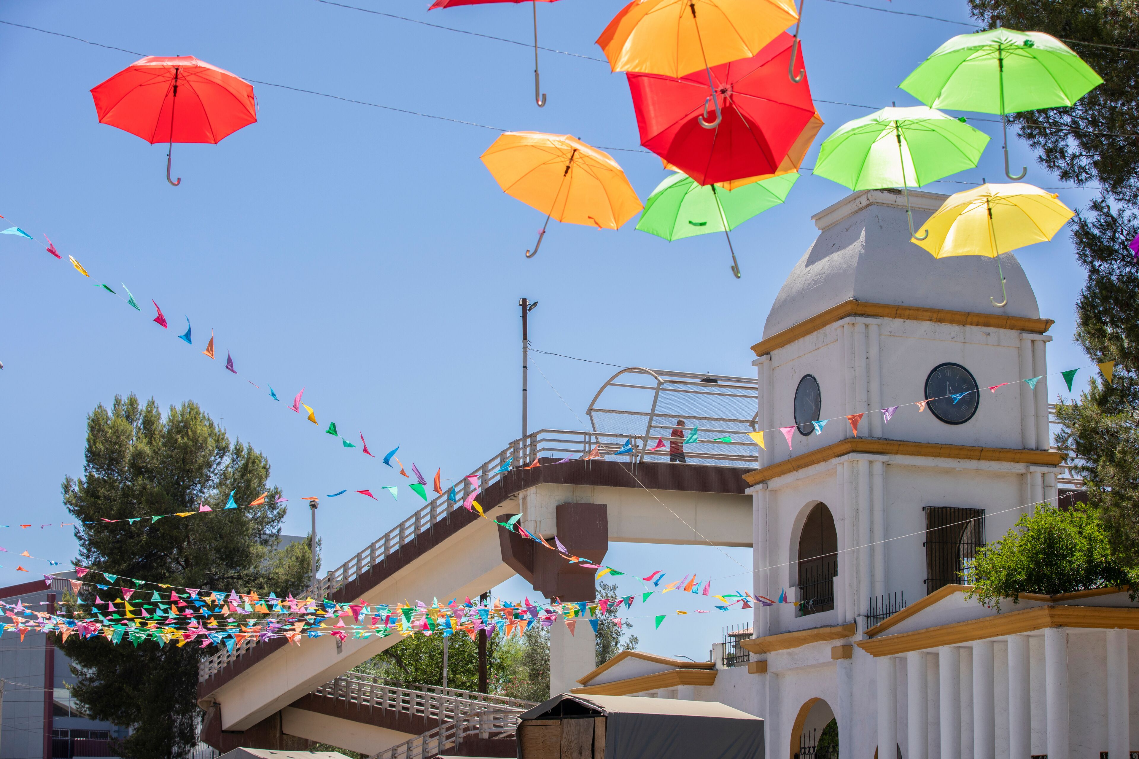 Colorful papel picado frames the historic clock tower of the downtown train station in Heroica Nogales, Sonora, Mexico.