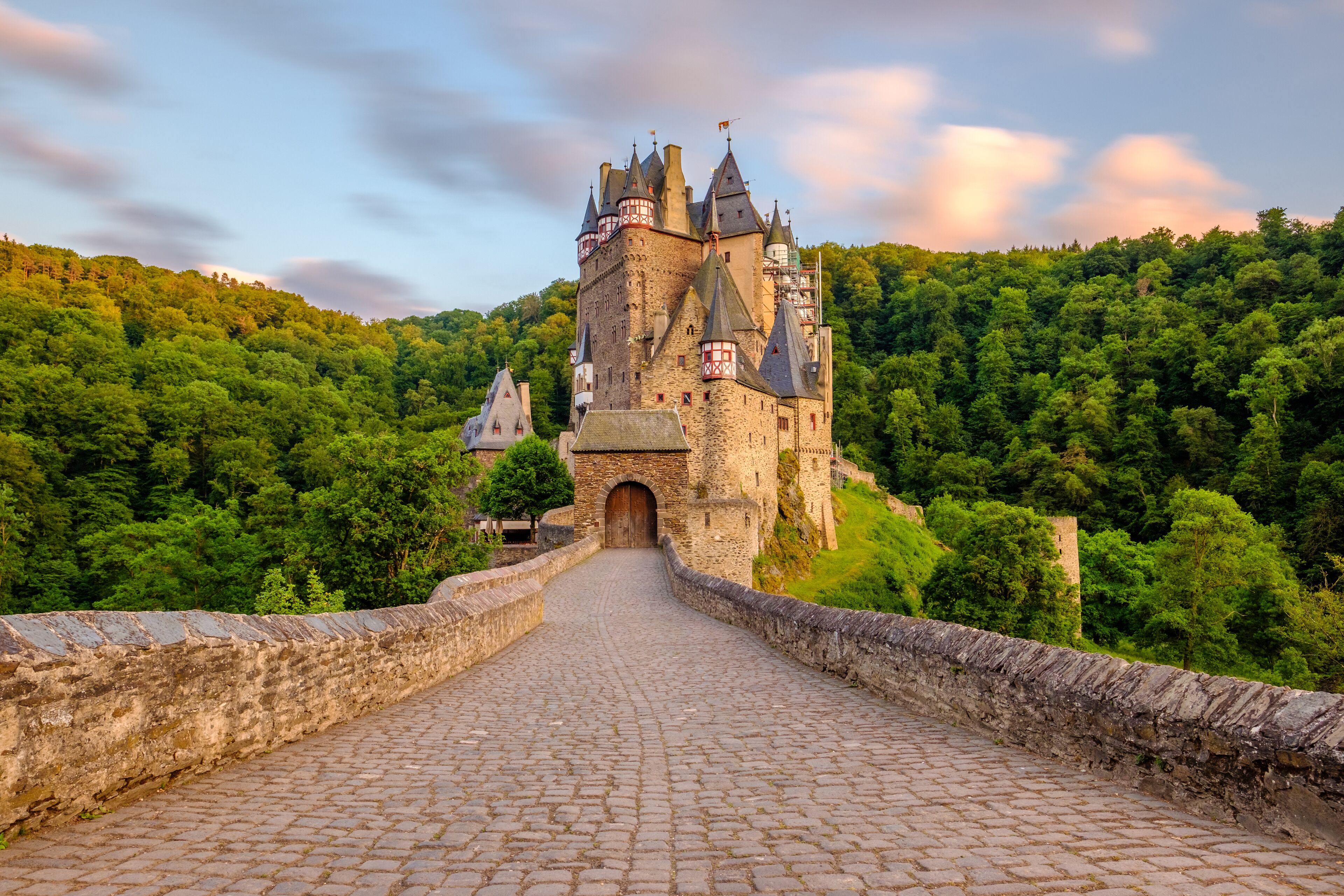 A castle on a hill with a cobblestone path leading to it.