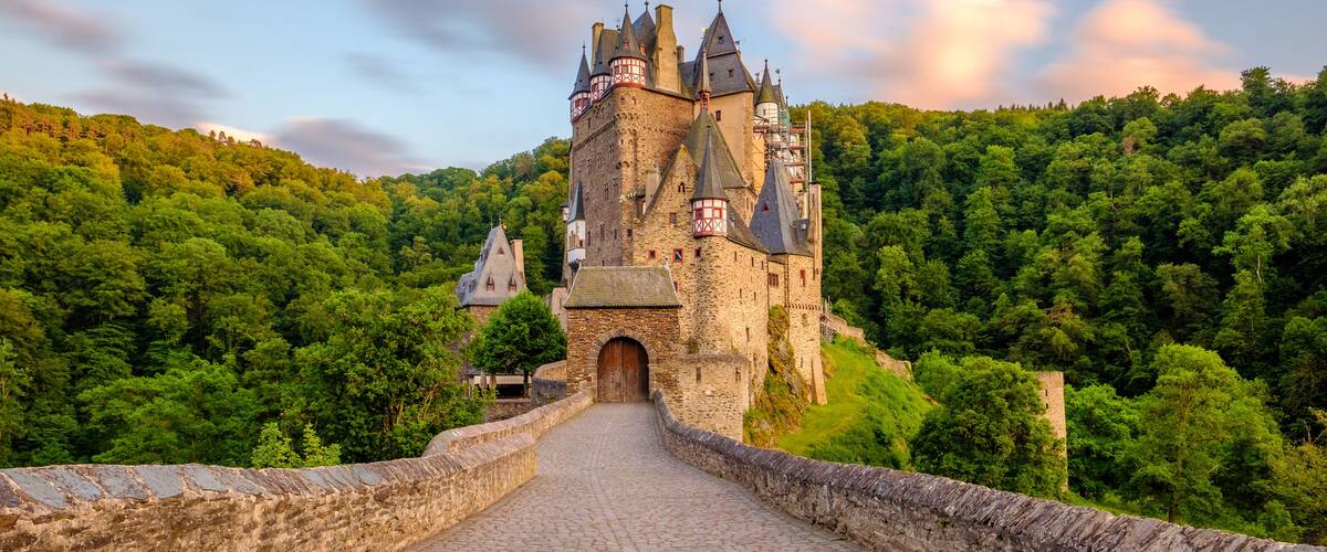 A castle on a hill with a cobblestone path leading to it.