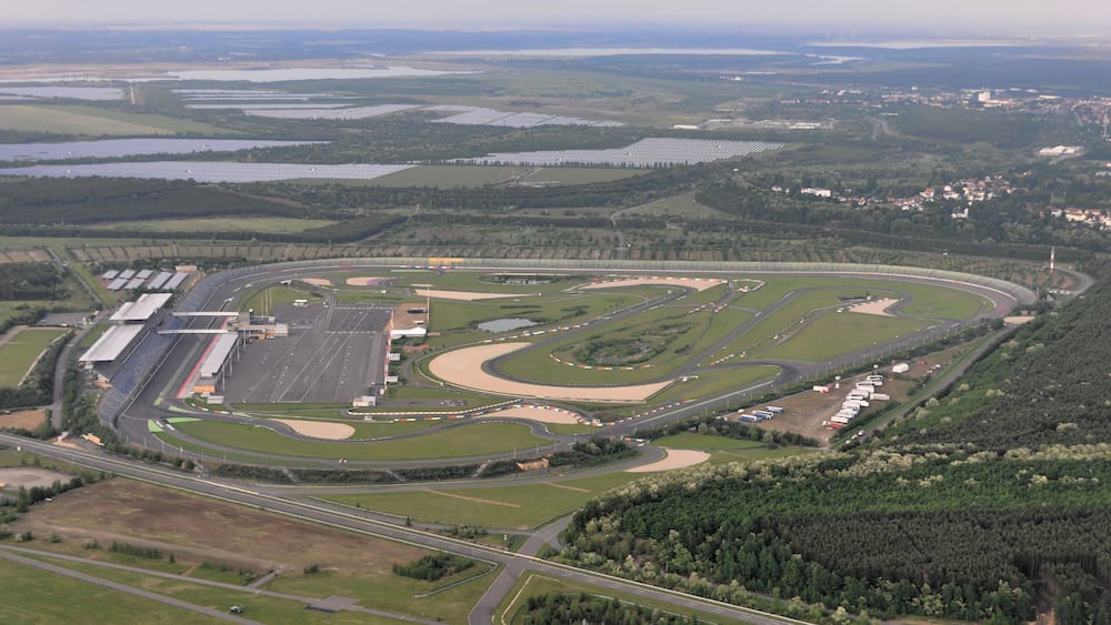 An aerial view of a race track surrounded by forests and water bodies.