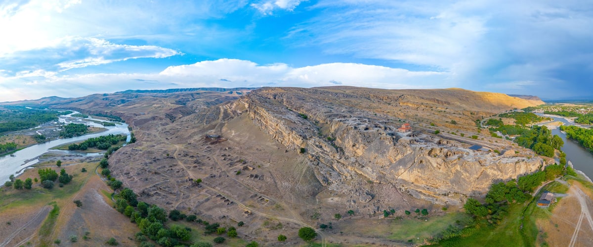 A mountainous landscape with a river, green vegetation, and a small settlement.