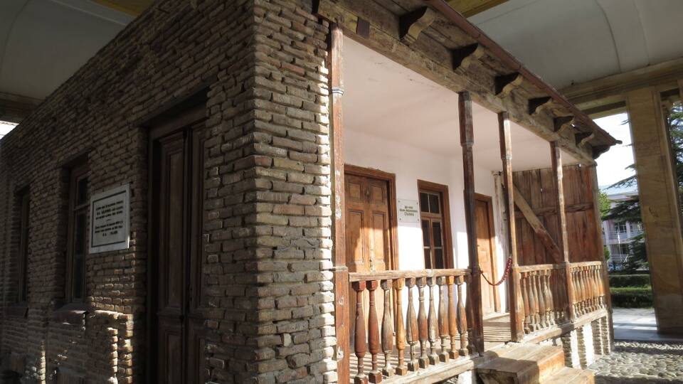 A brick building with wooden balconies and a staircase leading to a covered area.