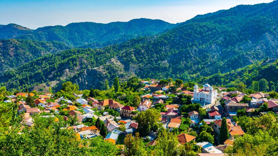 A village nestled in a valley surrounded by lush green hills.