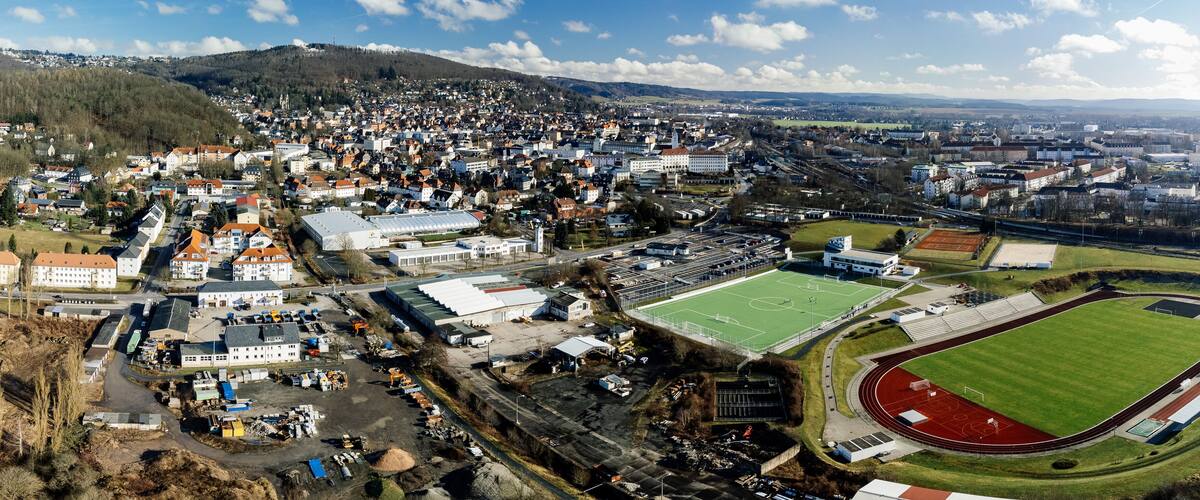 An aerial view of a town with a large stadium, a church, and surrounding residential areas.