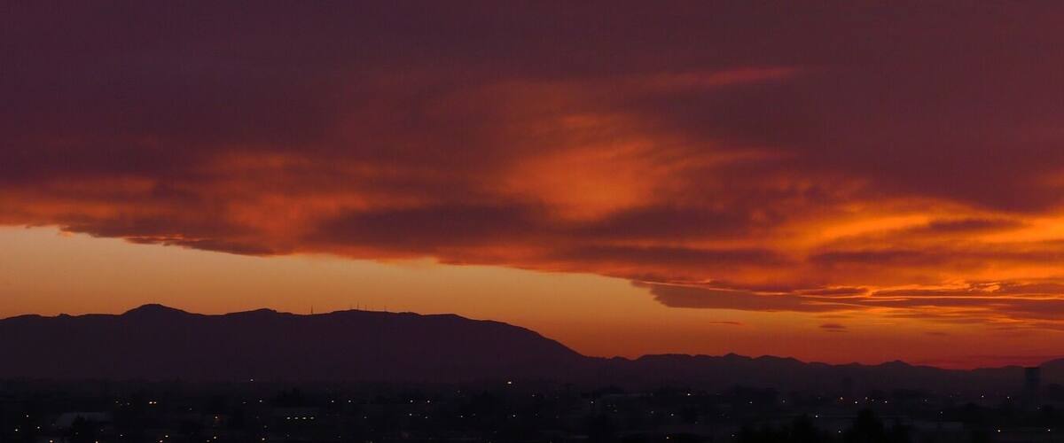 A sunset over a mountainous landscape with a city in the foreground.