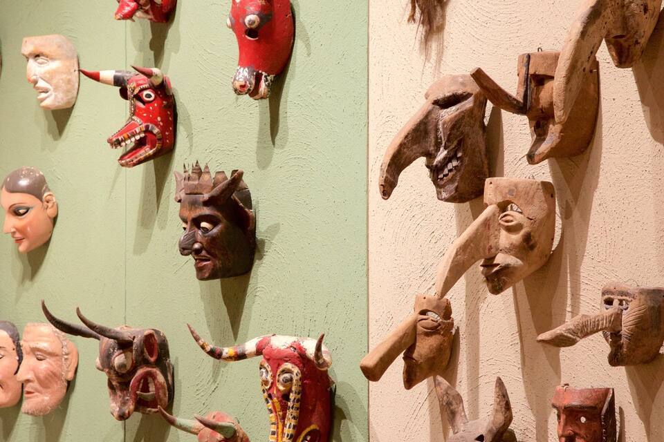 Una colección de máscaras talladas en una pared.