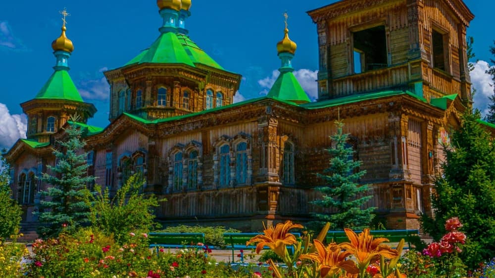 A historic wooden church with green domes and golden crosses.