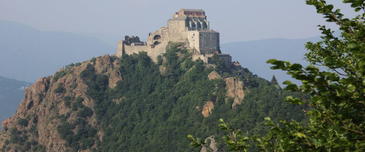 Un château historique perché sur une colline, entouré d’une forêt dense.