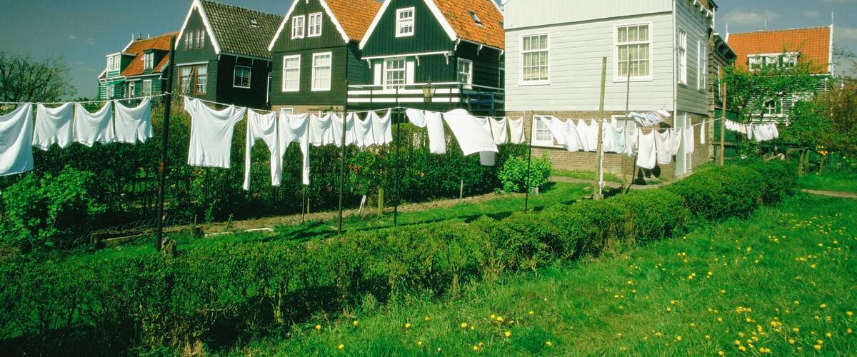 A row of colorful houses with laundry hanging on clotheslines in a lush green field.