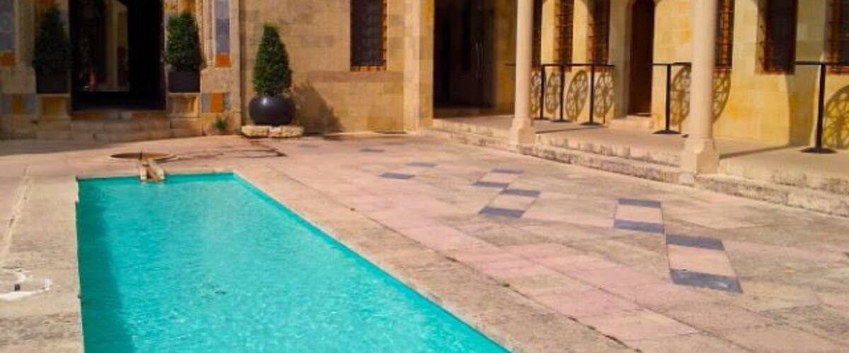A courtyard with a swimming pool, arches, and tiled flooring.