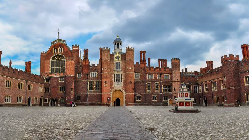 A historic building with a large central archway, surrounded by brick walls and towers.