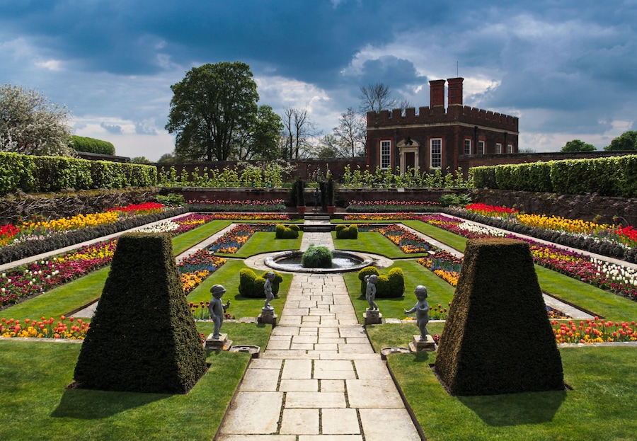 Moody rain clouds rolling into a sunny enclosed flower garden at Hampton Court palace, Surrey, England, UK; Shutterstock ID 326131079