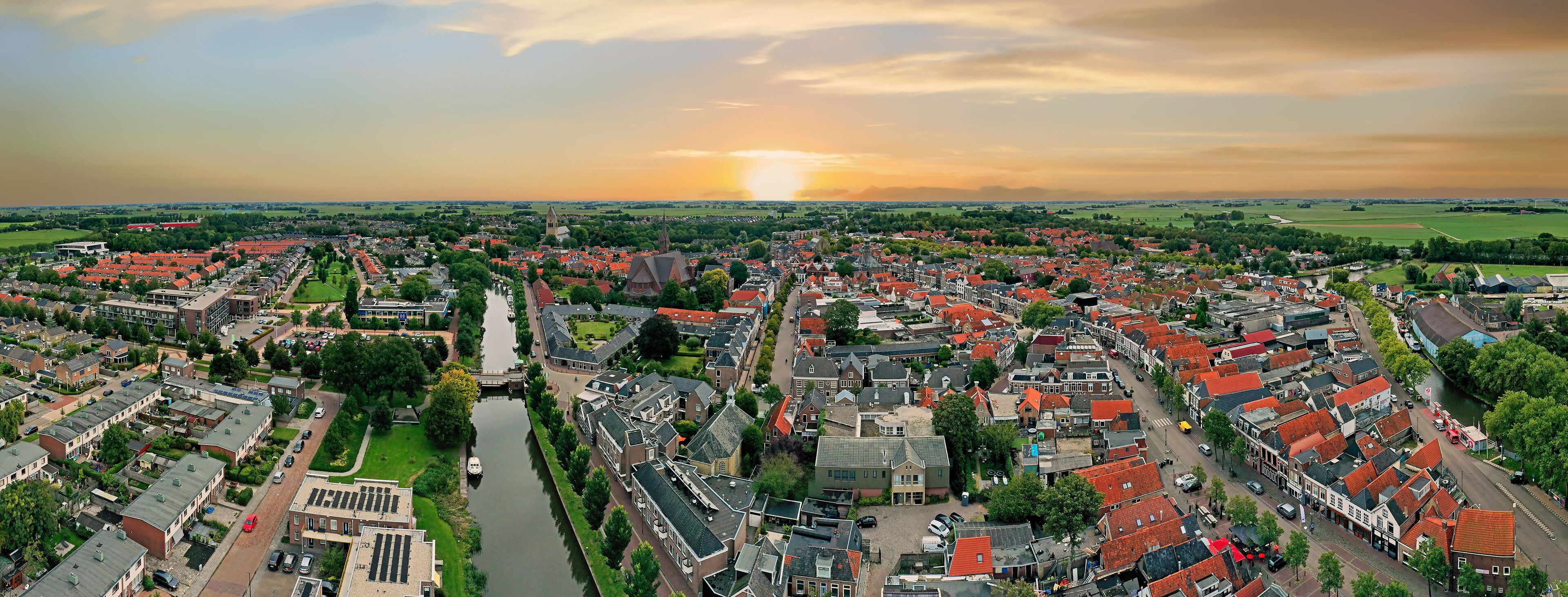 A panoramic view of a town with red-roofed houses, a river, and a church.