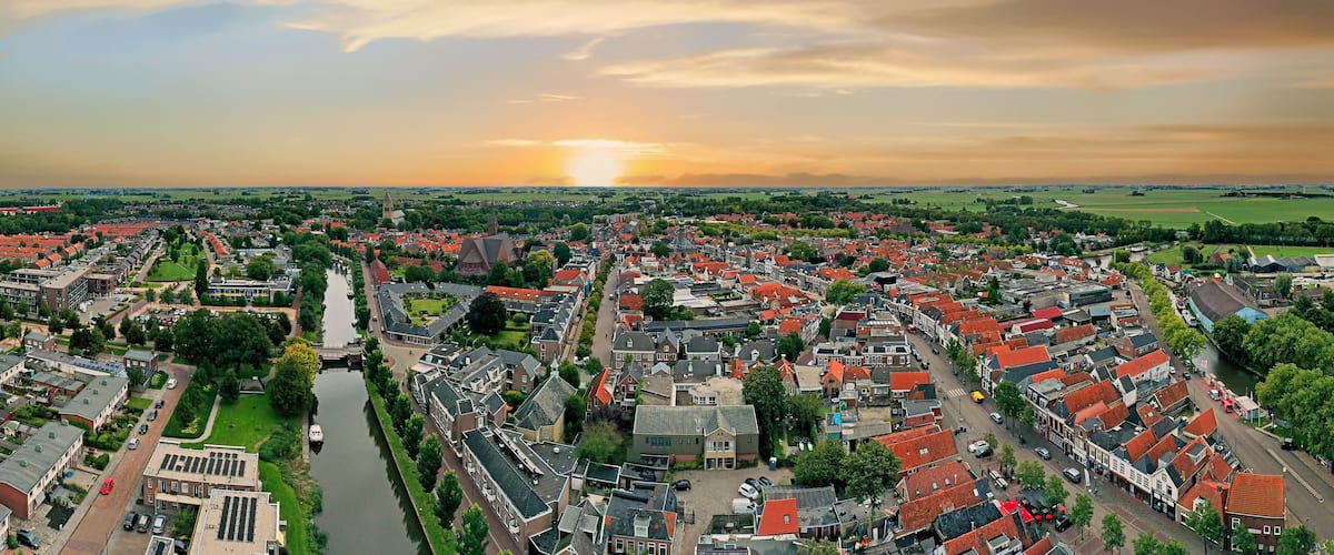 A panoramic view of a town with red-roofed houses, a river, and a church.