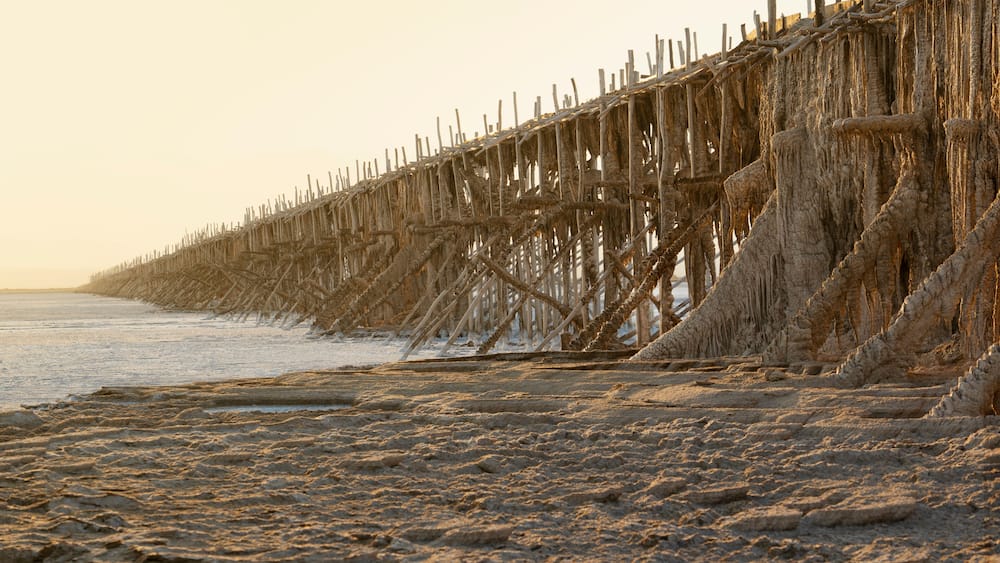 A beach with a deteriorating wooden pier extending into the water.