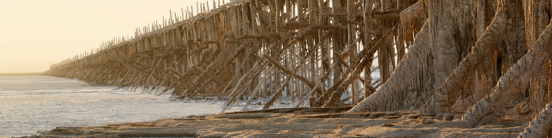 A beach with a deteriorating wooden pier extending into the water.