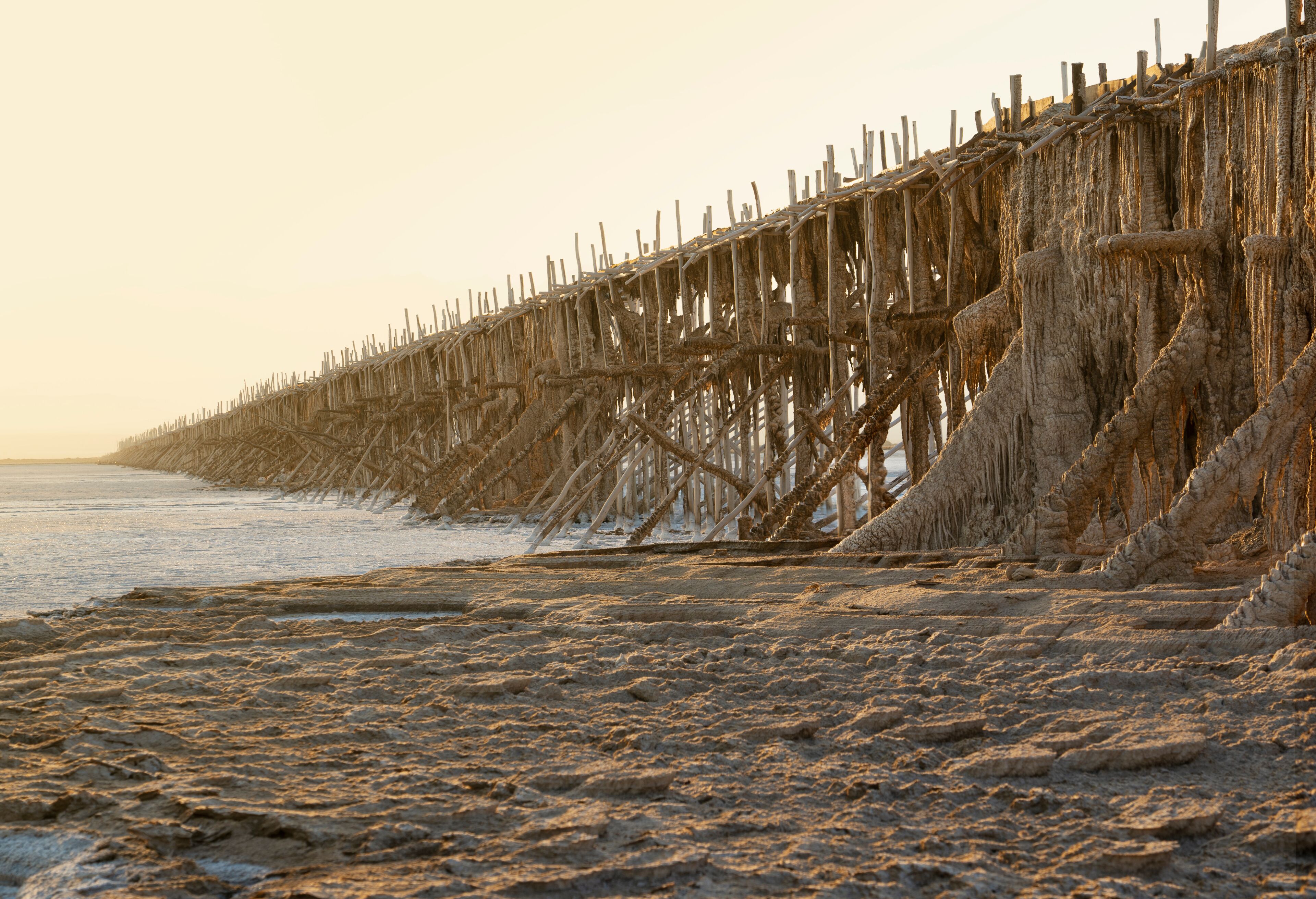 A beach with a deteriorating wooden pier extending into the water.