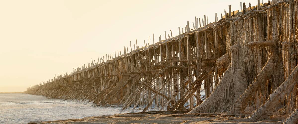 A beach with a deteriorating wooden pier extending into the water.