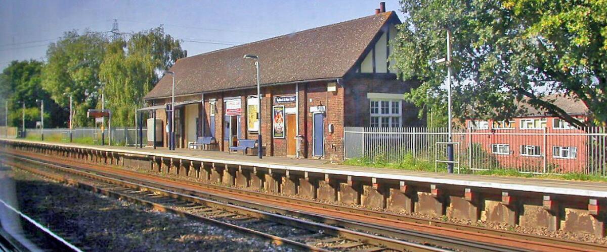 A train station with a platform, a building, and trees.