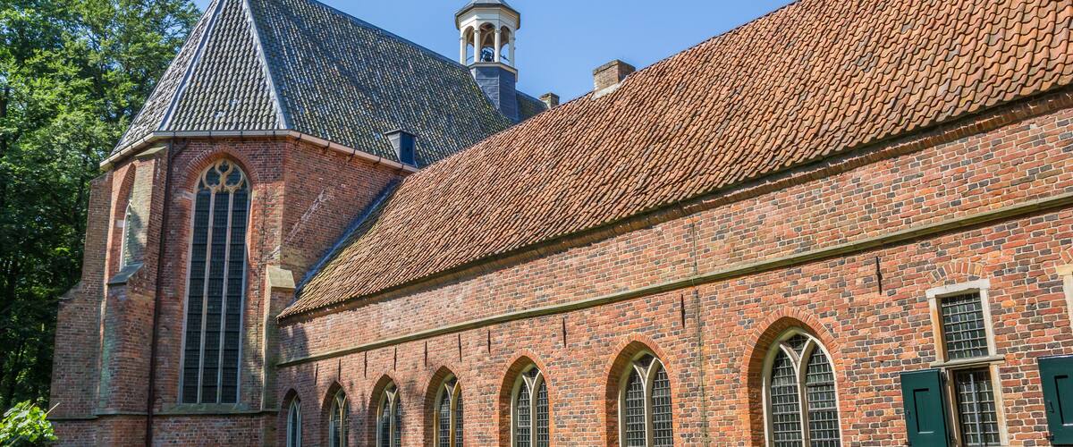 A historic brick building with a tiled roof and arched windows.