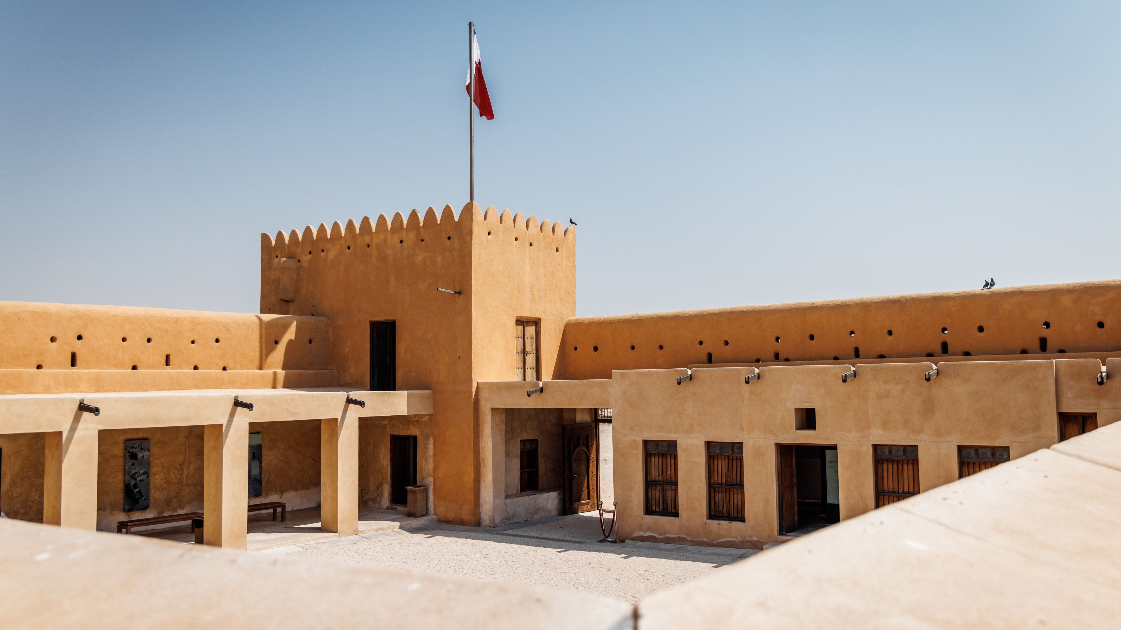 A traditional building with a flag, a tower, and a courtyard.