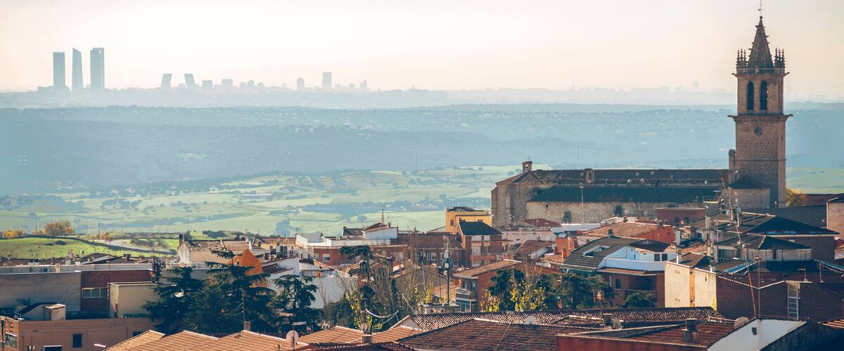 A cityscape with a prominent church tower, a castle, and modern buildings in the background.