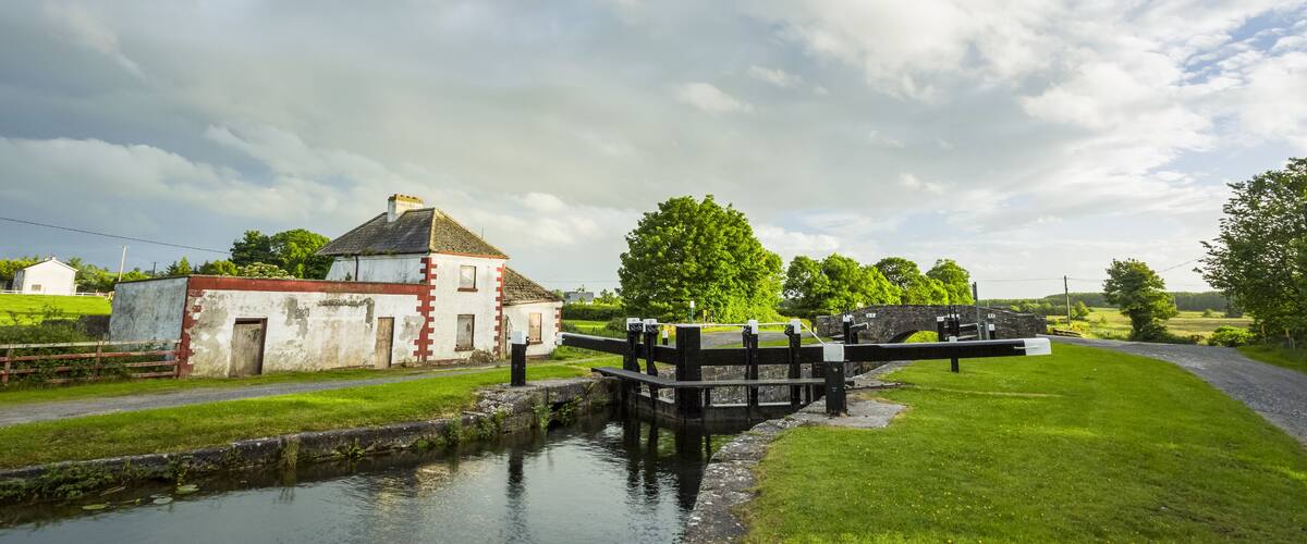 A canal with a lock and a white building with a red roof.