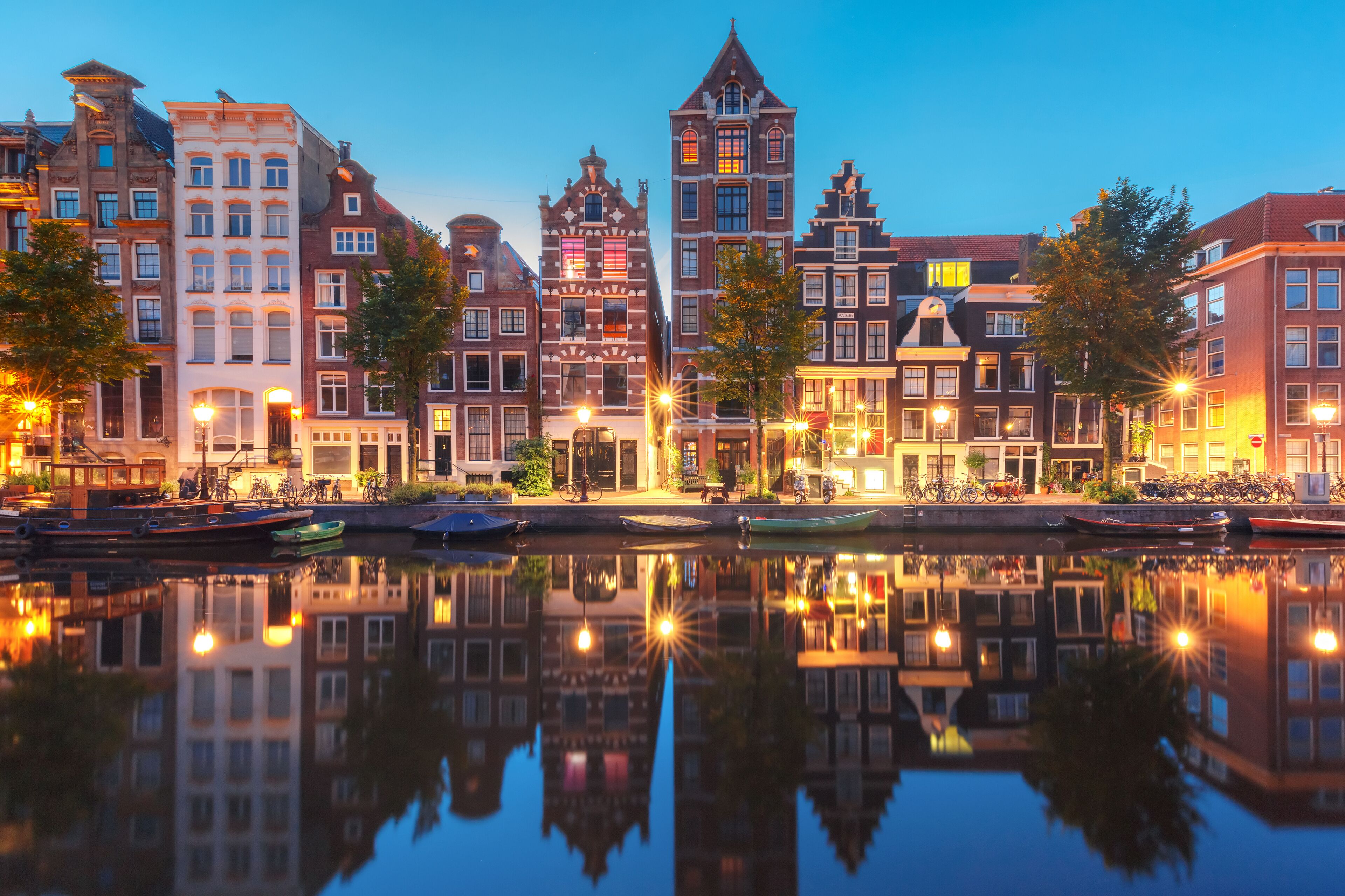 Amsterdam canal Herengracht with typical dutch houses and their reflections during morning blue hour, Holland, Netherlands.
