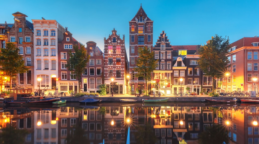 Amsterdam canal Herengracht with typical dutch houses and their reflections during morning blue hour, Holland, Netherlands.