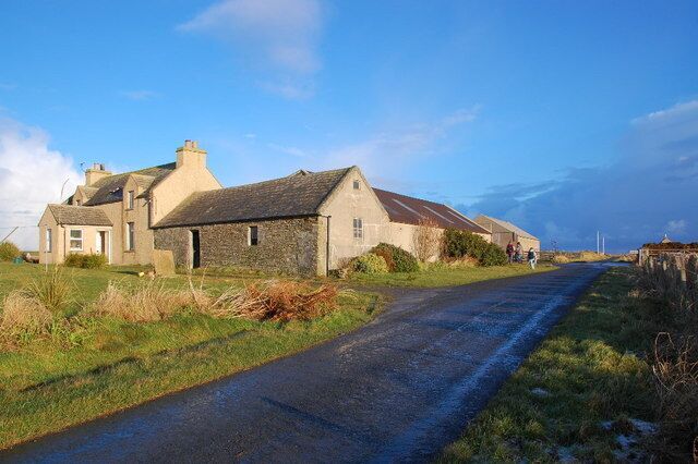 A rural road with stone buildings and a clear sky.