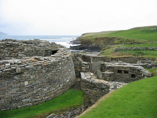 Ancient stone ruins by a coastal cliff.