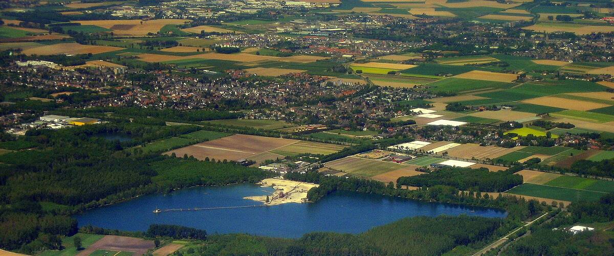 An aerial view of a rural landscape with a lake, agricultural fields, and a small town.