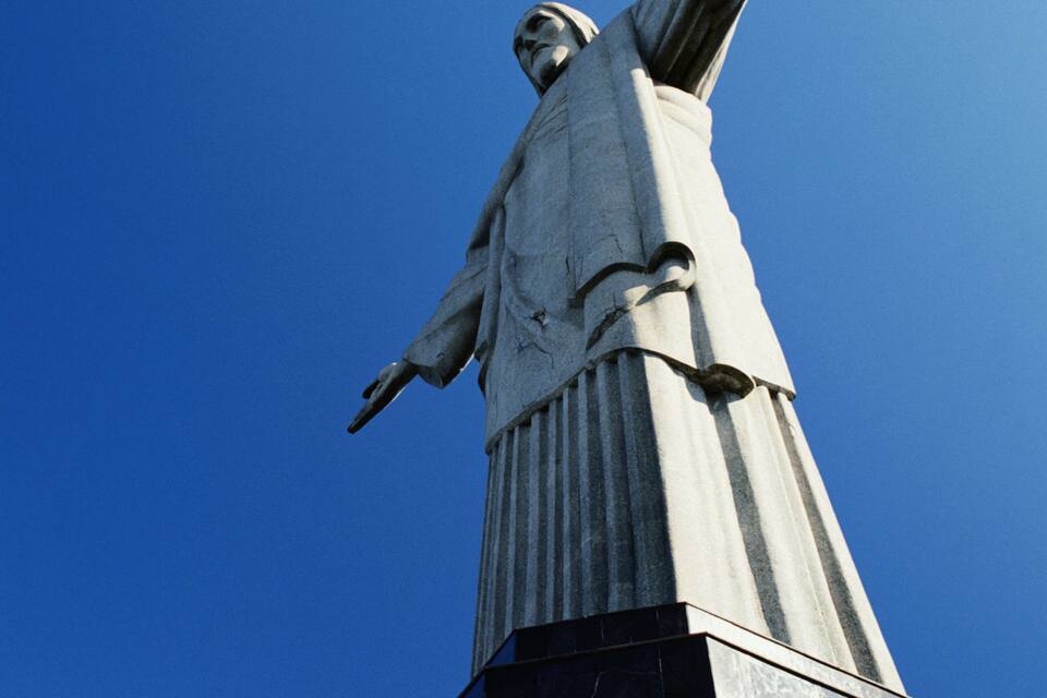 Una estatua con los brazos extendidos contra un cielo azul despejado.