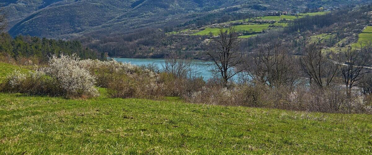 A mountainous landscape with a lake and green fields.