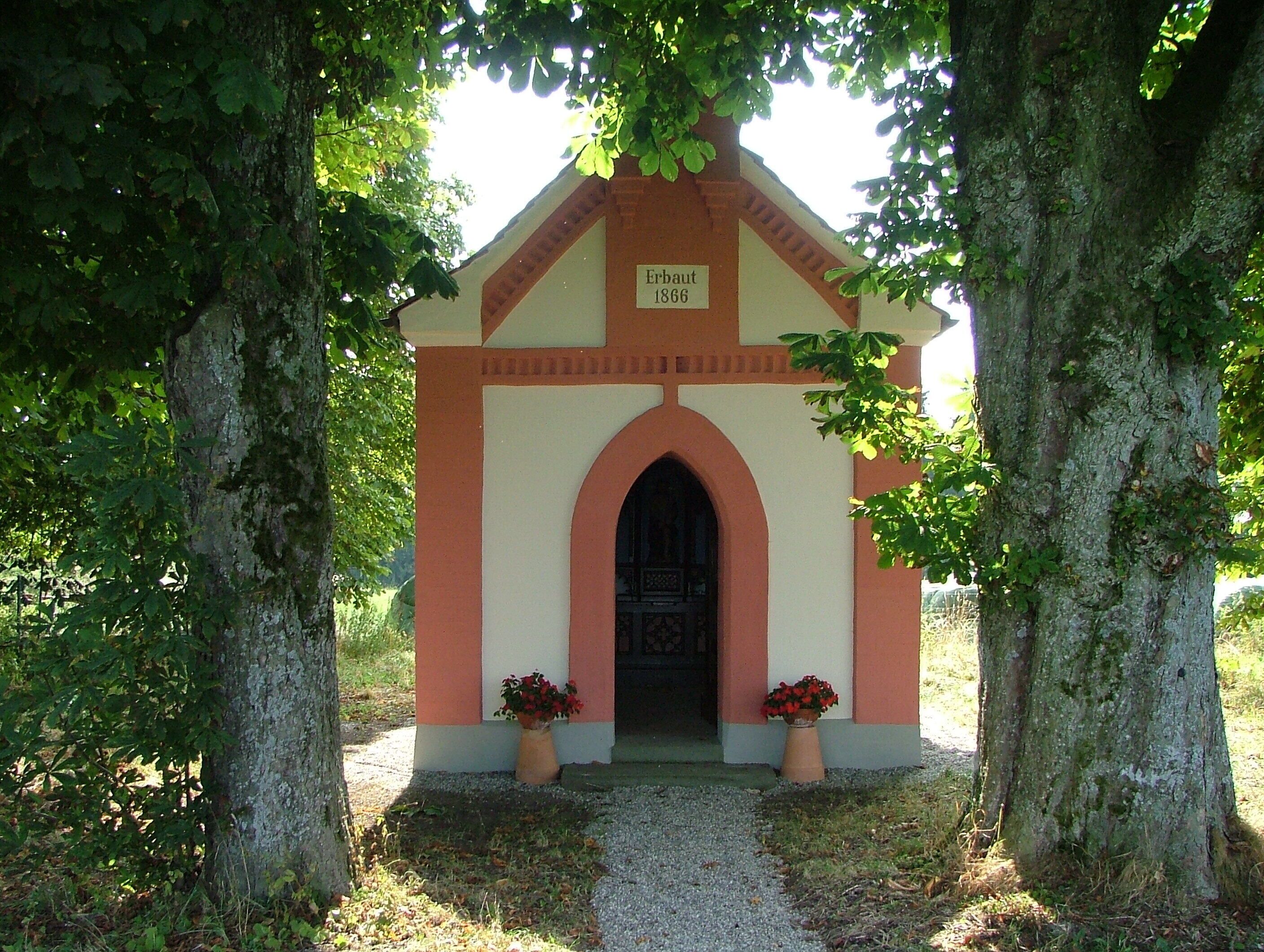 A small chapel with a date plaque reading "Erbau 1866" at its entrance.