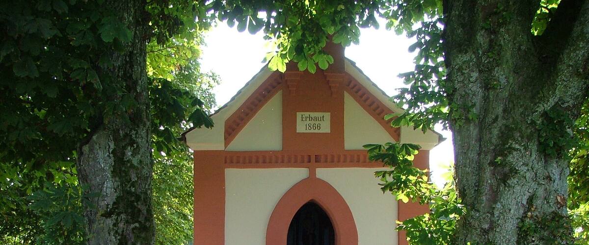 A small chapel with a date plaque reading "Erbau 1866" at its entrance.