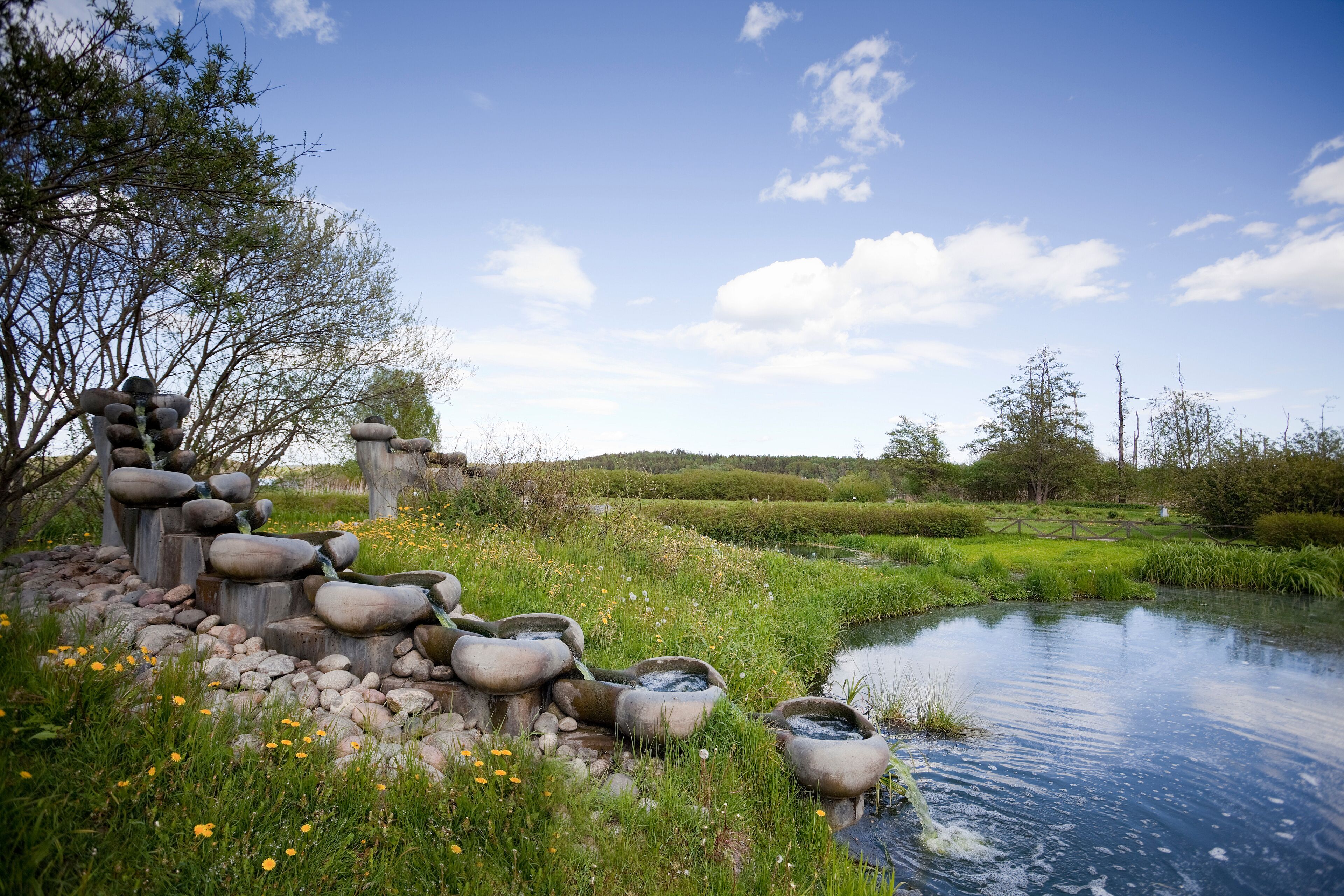 A serene pond with stone structures and lush greenery.