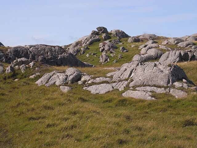 A grassy hill with large boulders and rocky outcrops.